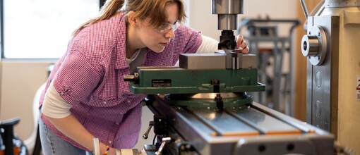 Mechanical Engineering student wearing protective eye gear using a large machine