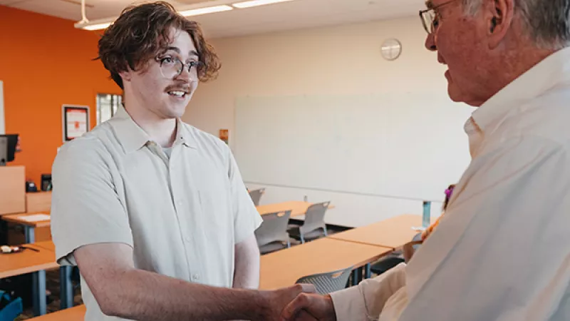 Student shakes hands with a professional at a networking event