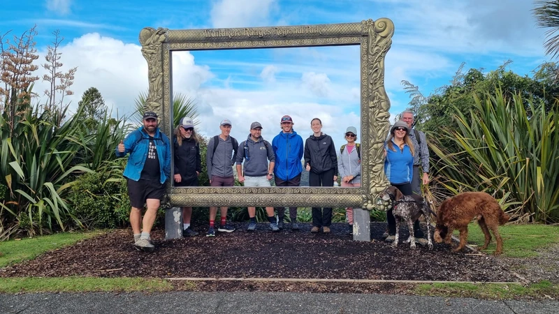 A group of people pose for the picture behind a life-size picture frame