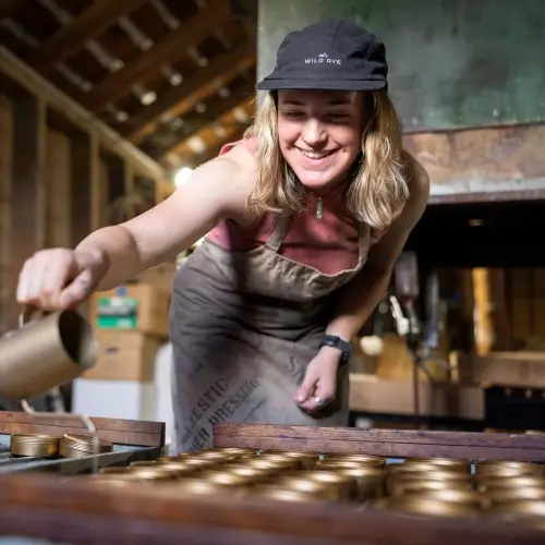 Person pouring liquid into a bunch of jars