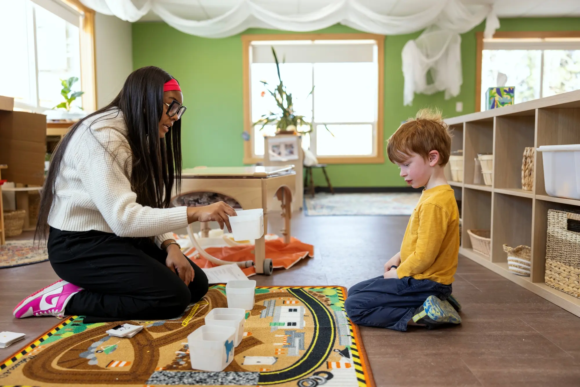 Early education student working with child showing them containers