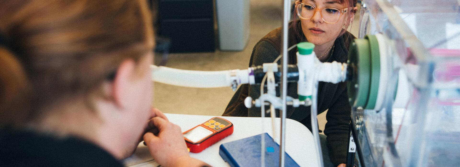 Person using machine during lab while looking at a red meter