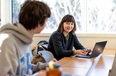 Two people looking at each other sat at a desk
