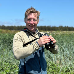Tom out in a field with binoculars