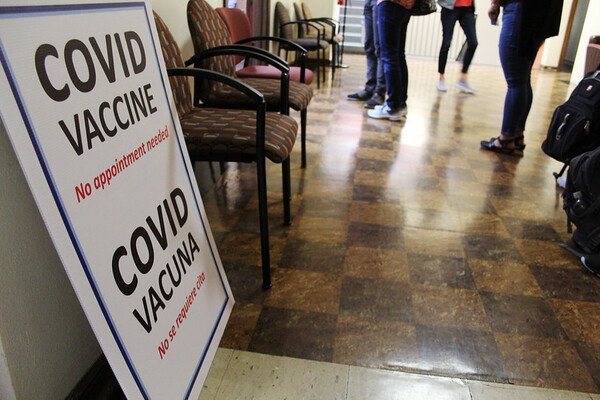 Sign for COVID vaccine with people's legs in the background