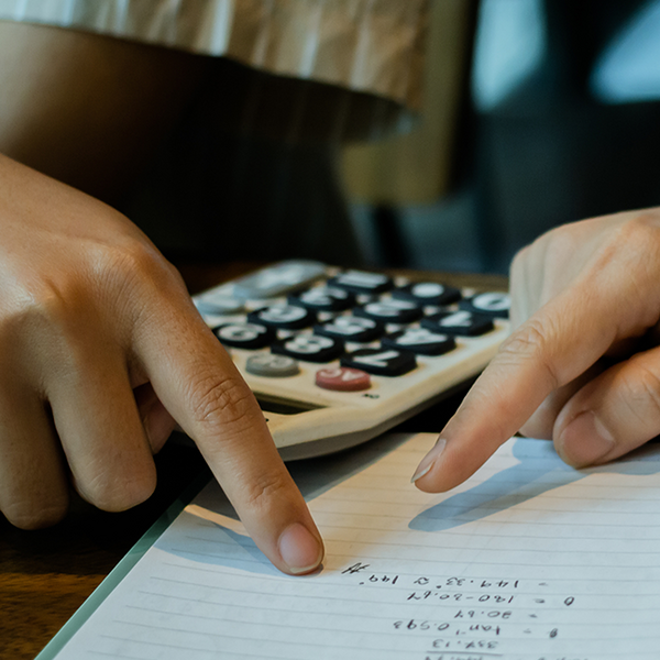 Fingers pointing to numbers with a calculator in the back